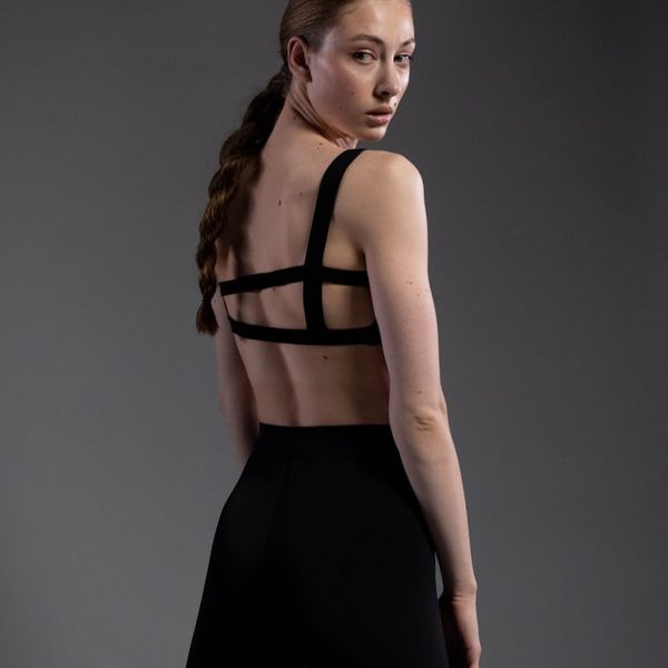 Person standing in a balanced yoga pose against a dark background.